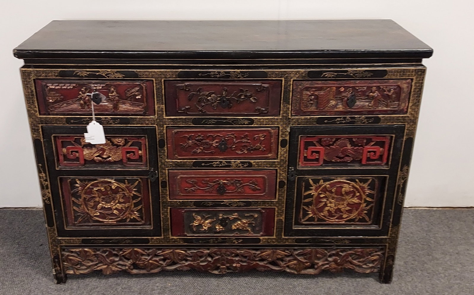 H1152 Chinese Style Chest of Drawers: Chinese chest of drawers: Black lacquer frame with gilt parcel decoration, 6 drawers, 2 doors. Drawers and skirt with relief carvings depicting figures, flowers, and foliage. Ill fitting drawers, scuf