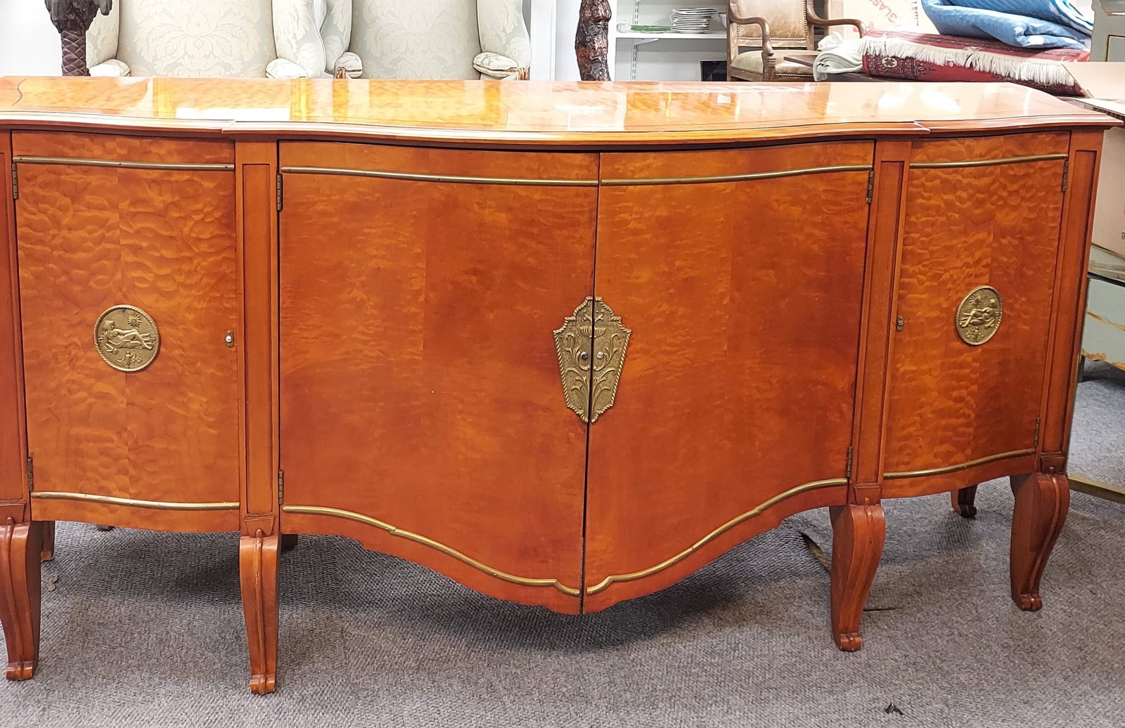H113 A Burled Serpentine Sideboard: A transitional serpentine sideboard with pieced burl veneers, inlaid top, 2 bowed center doors, 2 side doors, inner shelves in each cabinet, round bronze medallions on each side door, a divided bronze