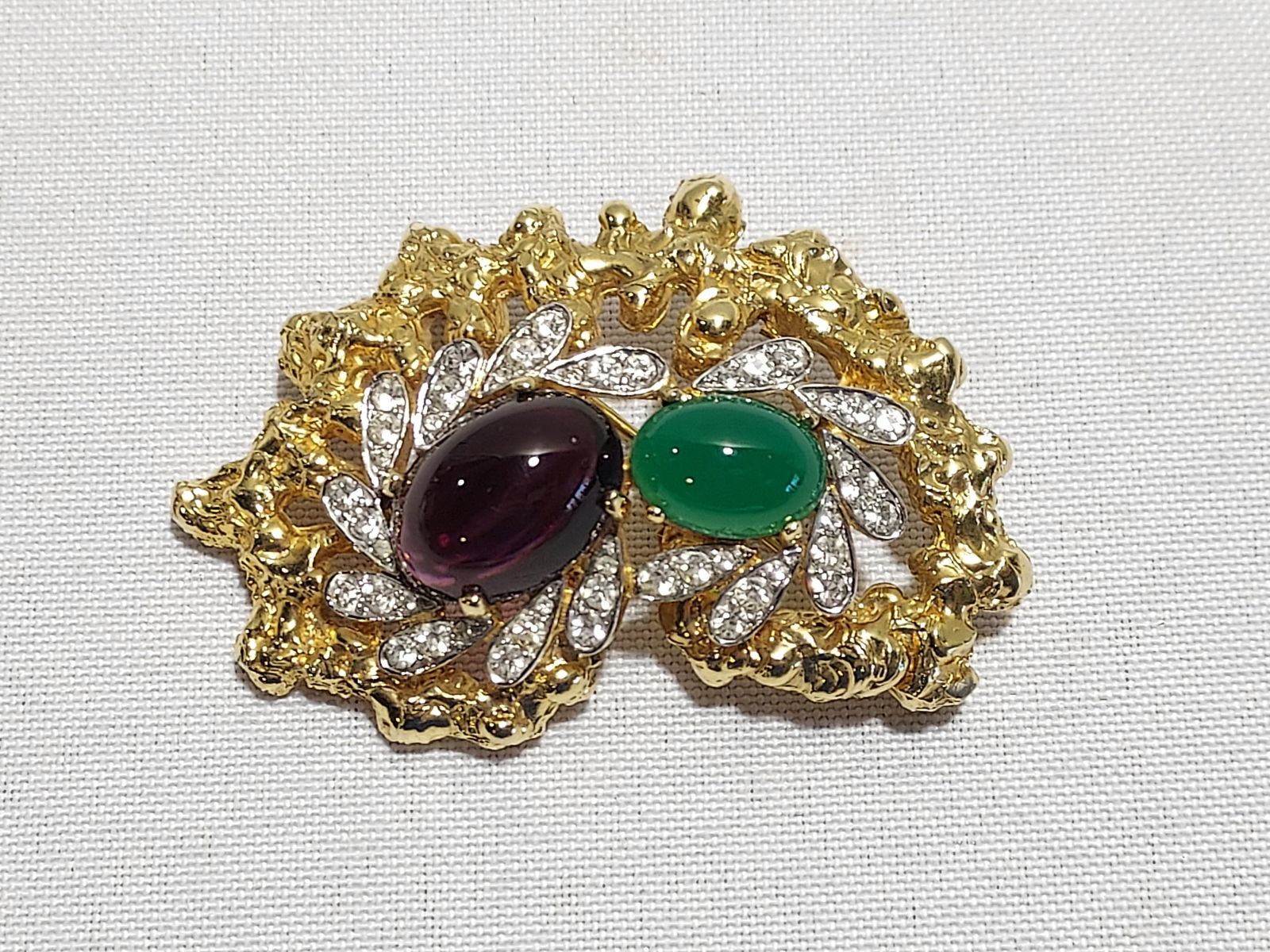 H597 Jomaz gold finished brooch: Jomaz gold finished brooch: faux amethyst and faux jade, and clear rhinestone brooch. 2.5" wide.