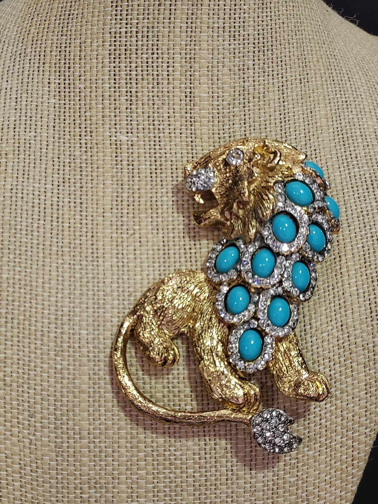 H593 Kenneth Jay Lane Prideful Lion brooch: Kenneth Jay Lane Prideful Lion brooch: Gold tone metal lion form with clear rhinestone accents to muzzle, tail, and eye and faux oval turquoise blue beads to mane. Signed Kenneth Lane made in USA. 3.2