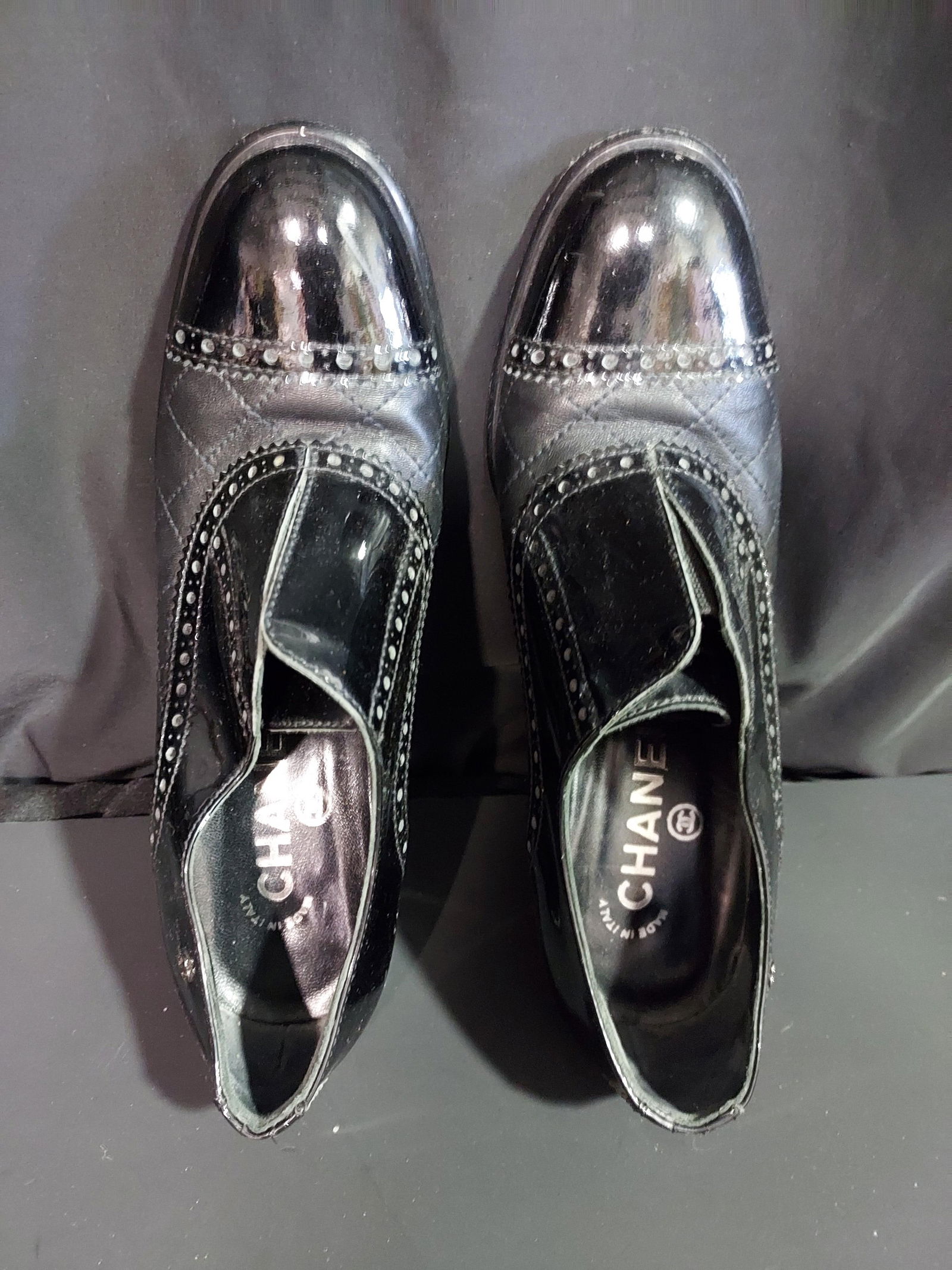 H722 Chanel black ankle booties: Chanel black ankle booties. Black brogue-style ankle booties with quilt pattern, patent leather toe caps, 3.5” heels, and small silver tone CC logos on the side. Circa 2004. Scuffed soles for gr