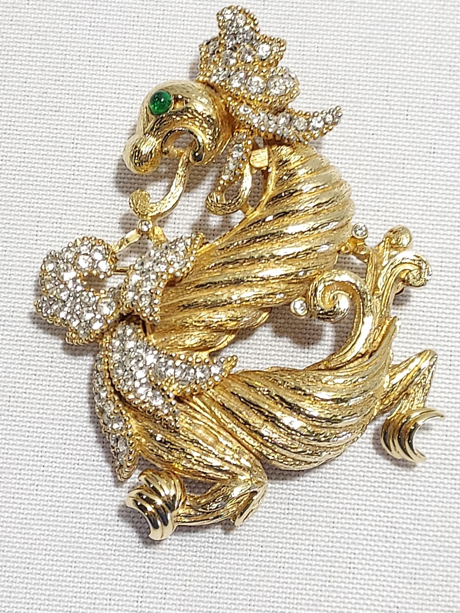H591 Ciner dragon brooch: Ciner dragon brooch: Gold tone metal, clear rhinestones and green cabochon glass eyes. Signed Ciner. 2.75"