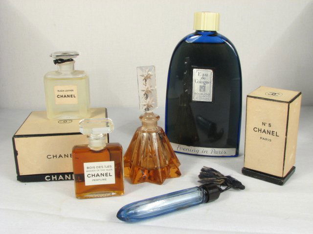 SIX GLASS PERFUME BOTTLES, ETC.: Lot of six glass perfume bottles and more. Includes "Russian Leather" Chanel, "Bois Des Iles" by Chanel, a small blue glass bottle, a star shaped orange glass bottle with stopper, a larger blue glass
