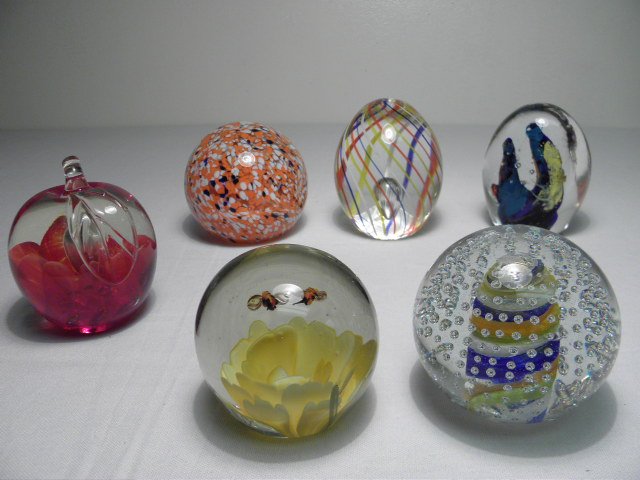 SIX ART GLASS PAPERWEIGHTS: Lot of six art glass paperweights. Includes a spherical 3.75" tall orange floral paperweight, an egg shaped multi-color 4" tall paperweight with controlled bubble, a 4.2" tall multicolor paperweight, 