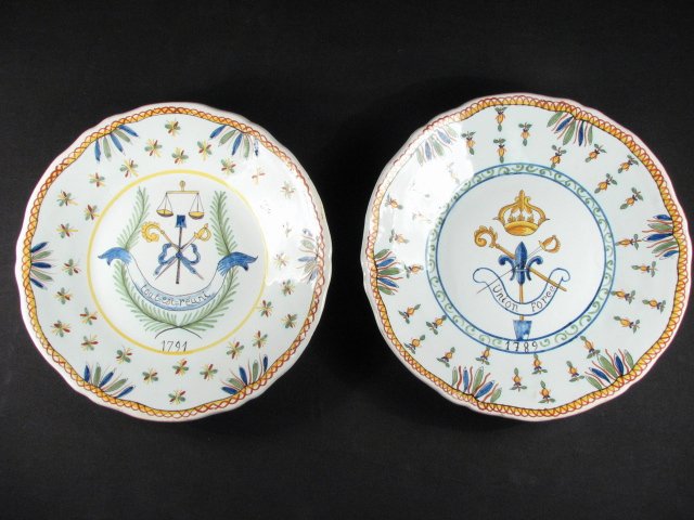 TWO FRENCH FAIENCE ARMORIAL PLATES: French faience armorial plates. Both measures 9.6" in diameter and have a polychrome glazed finish. One plate is decorated with a balance scale coat of arms, reads "Tout est reuni" (Everything is conv