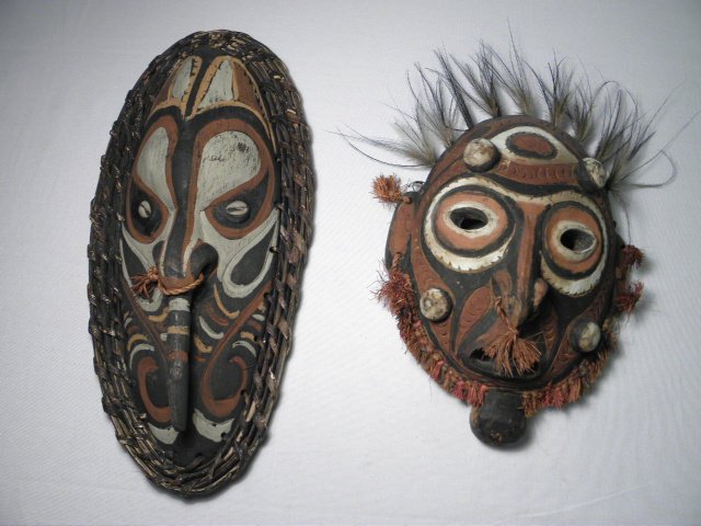 TWO SEPIK RIVER, PAPUA NEW GUINEA CARVED WOOD MASKS: Lot of two Sepik River area, Papua New Guinea spiritual carved wood masks. One has applied reeding and cowrie shells for eyes, the other has applied straw and feathers. Condition: generally good, very