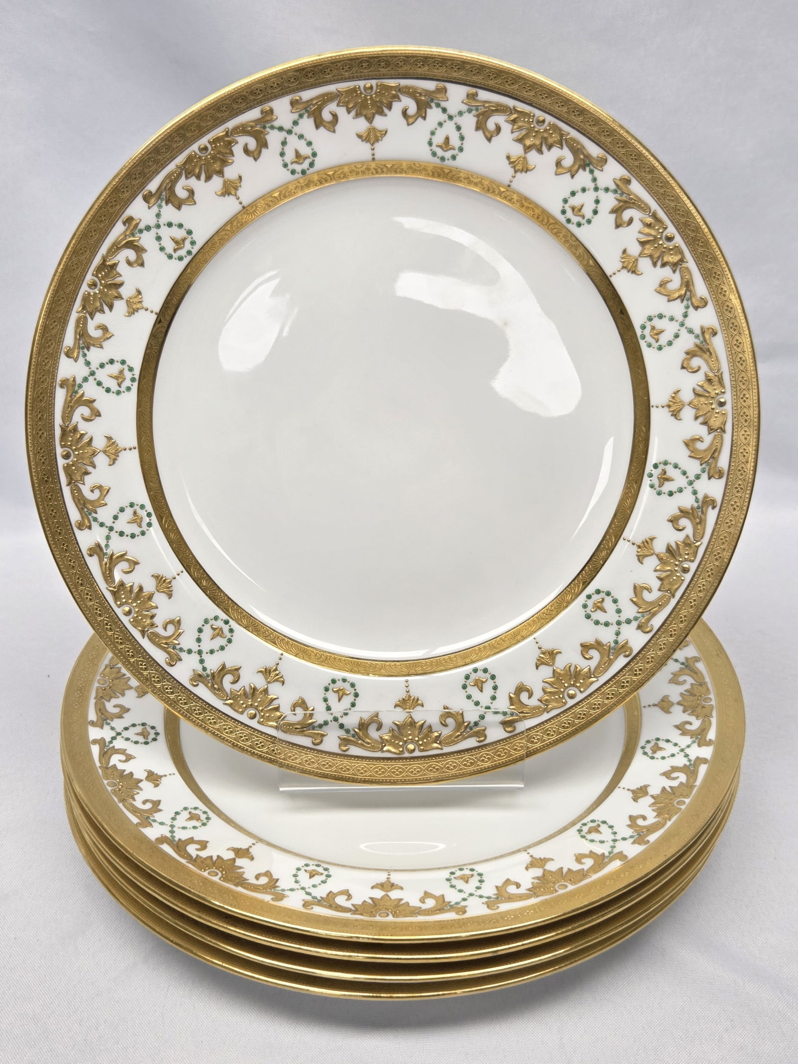 MINTONS TATMAN CHICAGO DINNER PLATES 5 pc: Five elegant Mintons Tatman Chicago dinner plates. These plates feature an intricate gold border complemented by green enamel jewels, showcasing the exquisite craftsmanship typical of Mintons porcelai