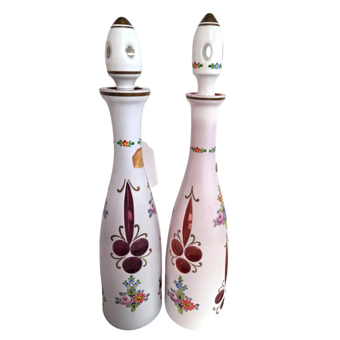 PR BOHEMIAN CUT- CRANBERRY CASED GLASS DECANTERS: Pair of Bohemian white overlay cut to cranberry cased glass decanters with stoppers. Each decanter measures 15.5"H x 3.5" W Condition is good with no chips, cracks, or visible wear.SHIPPING NOTELive A