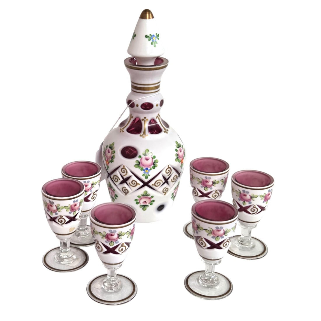 7 PC BOHEMIAN CUT TO CRANBERRY GLASS DECANTER SET: 7 pieced decanter set consisting of a decanter 9.5 with stopper and 7.5" without and six small stems 3.5" x 2". Each item decorated with a hand painted floral design and gold trim. SHIPPING NOTE: