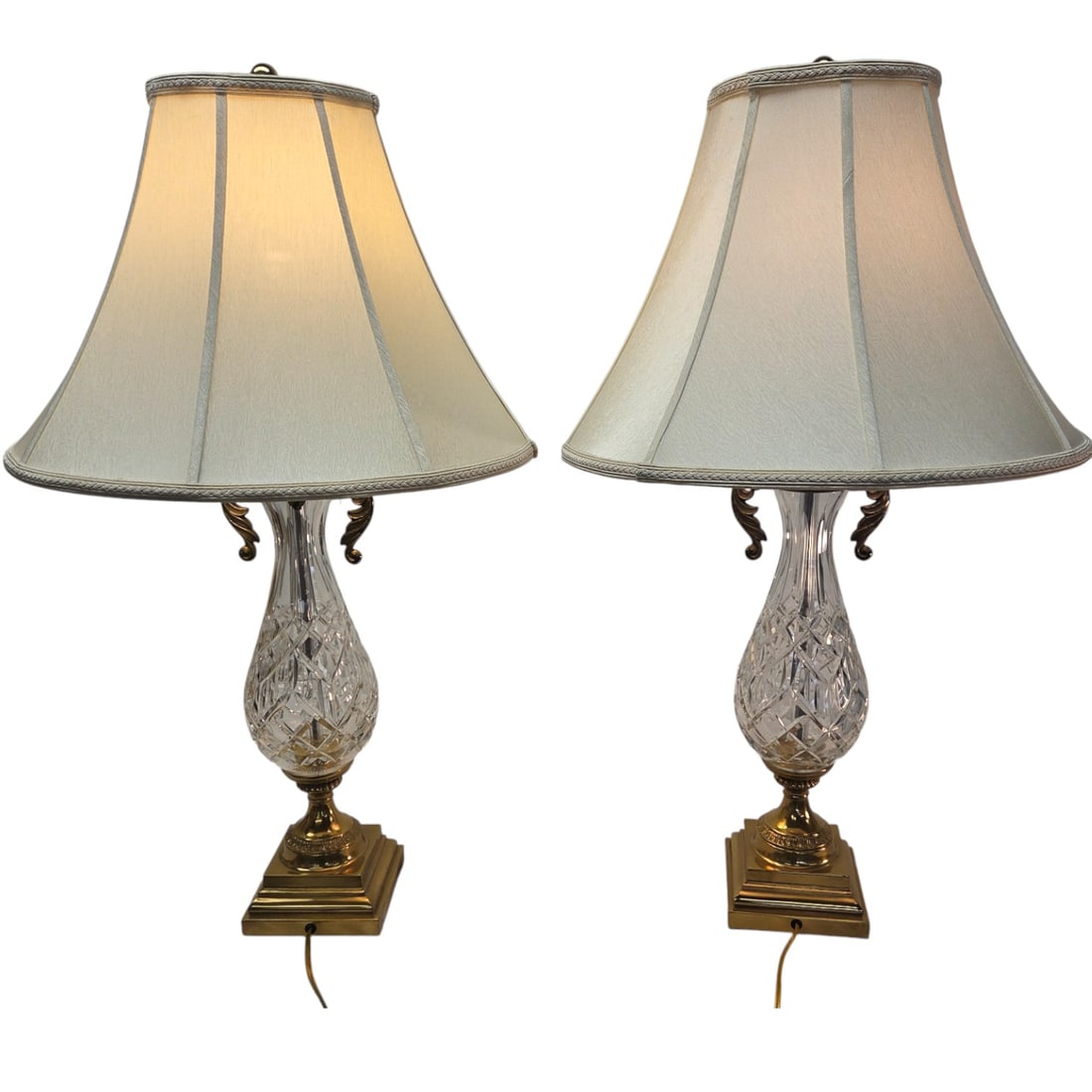 SET OF 2 WATERFORD GLASS LAMPS W/ SILK SHADES: Set of two Waterford glass lamps with ivory/cream colored silk shades, and brass accents. These lamps have a urn- shaped body with distinct crystal cut pattern. One has original Waterford sticker. Bot