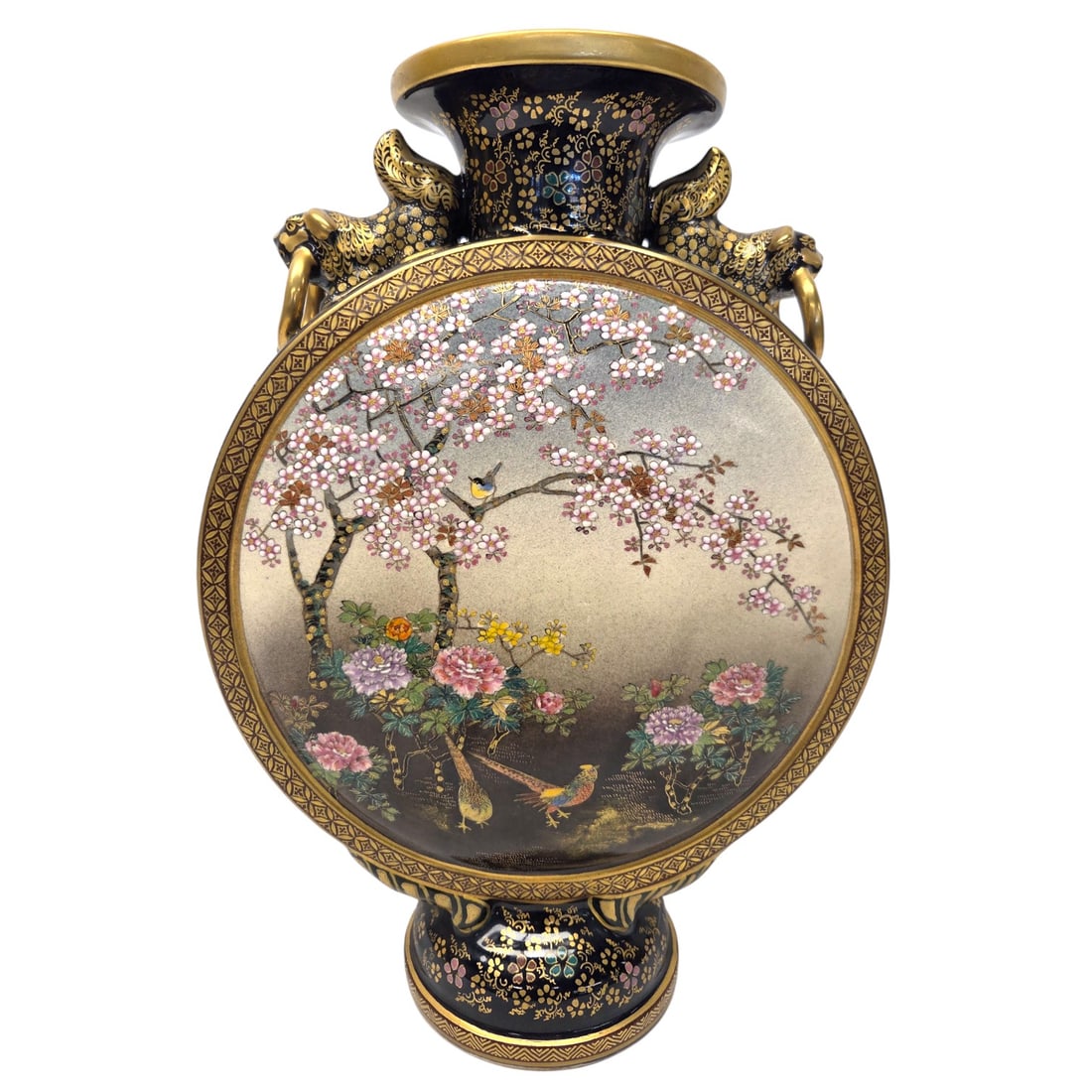 JAPANESE SATSUMA MOON VASE FLASK FOO DOG W/ RINGS: Japanese Satsuma Meiji Period moon flask vase hand painted with gold gilt over blue ground floral motif designed with foo dog ring handles. Circa: Early 20th Century. Artist signed. 12" X 9" X 4". Sma