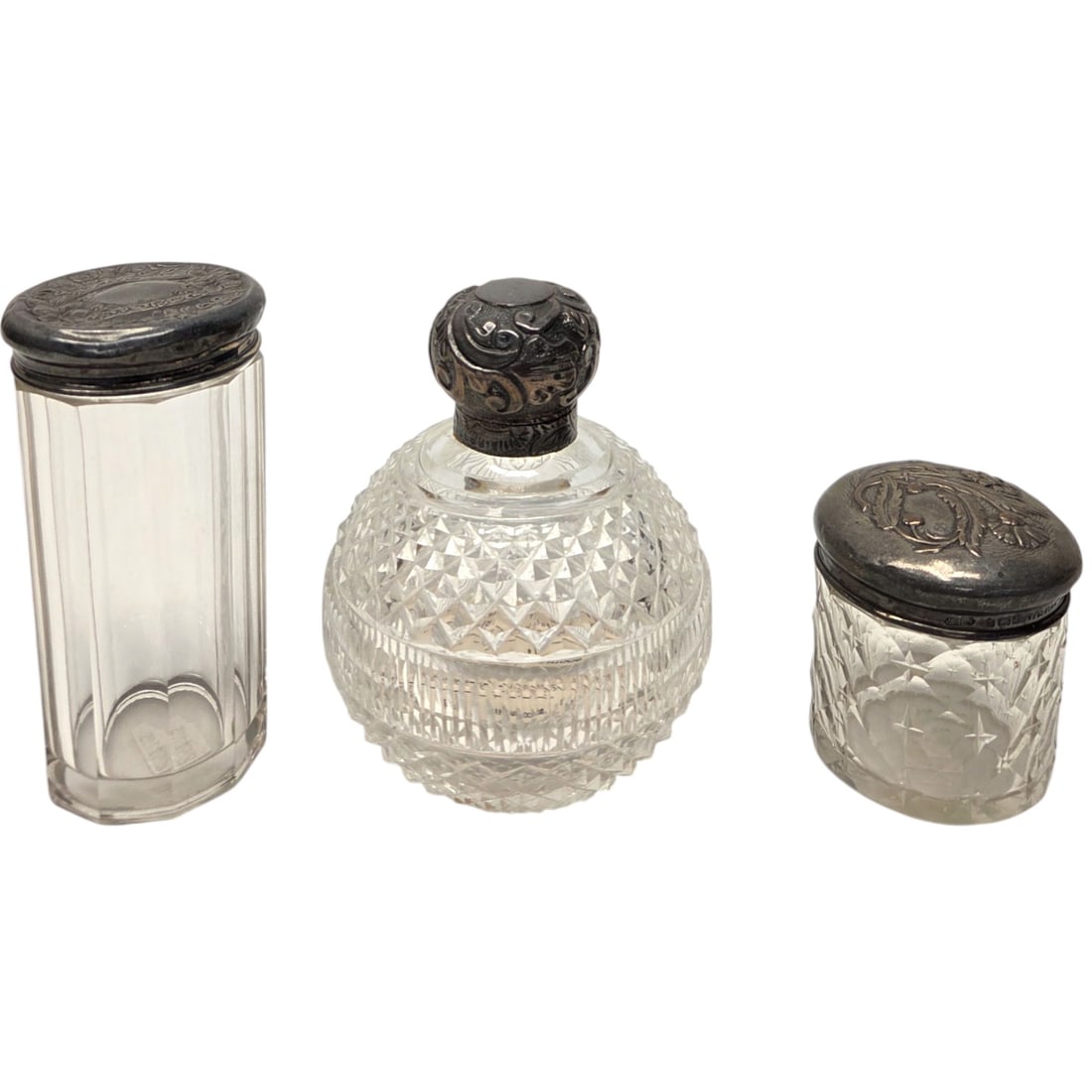 3PC STERLING SILVER TOPPED GLASS VANITY JARS: Three sterling silver topped cut glass vanity jars. Stamped sterling. See photos. Each measures 4.5" H x 4"W, 4.25" H x 2. 25W", and 2. 25"H x 2. 25"W. Good condition.SHIPPING NOTE: Live Auctioneers o
