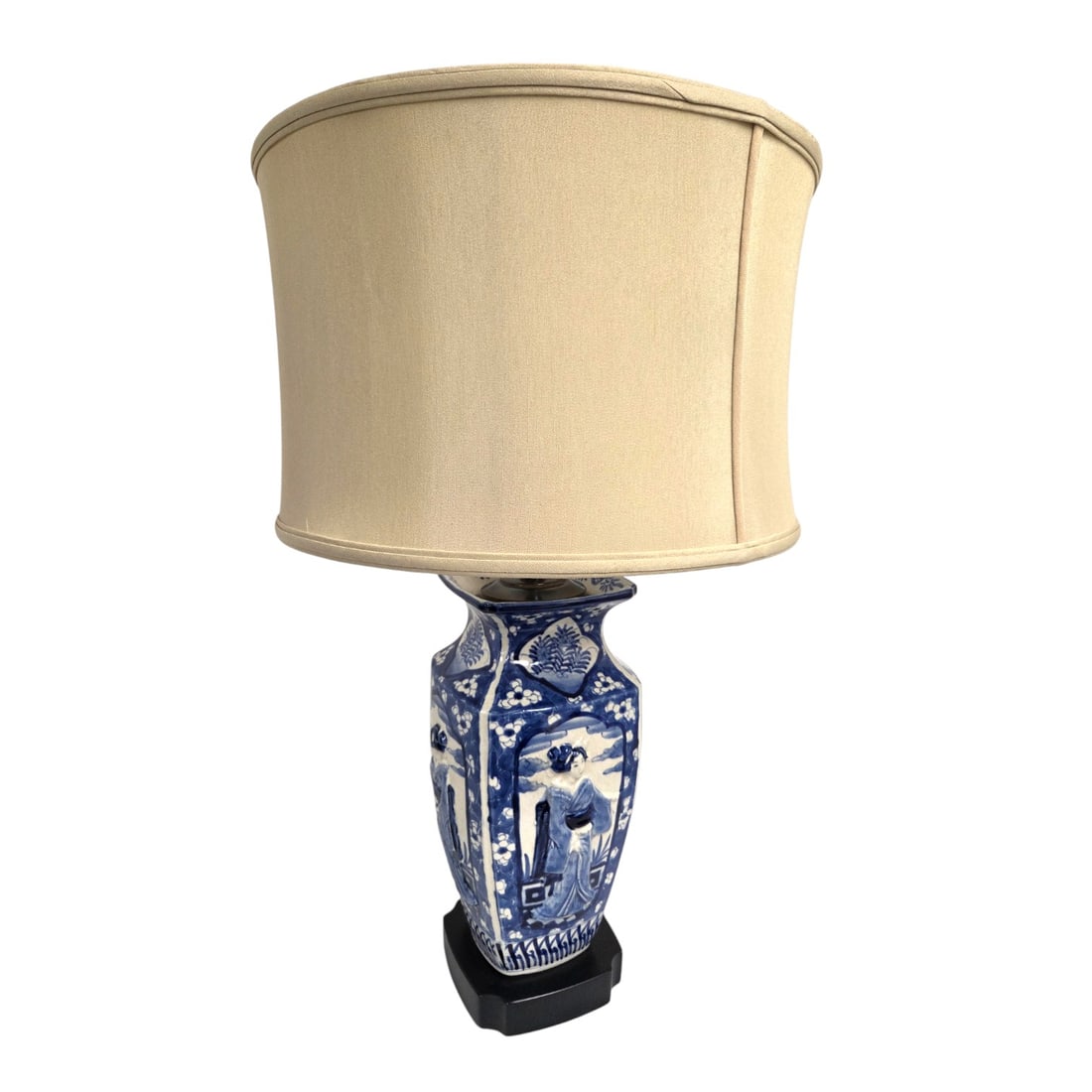 VINTAGE BLUE & WHITE ASIAN CERAMIC LAMP: Early to mid 20th C blue and white Asian ceramic lamp. 4-panels each with a relief of a female figure framed by blue and white prunus flowers. Light tan silk shade. Black base. Measures 23.5" H x 7.5"