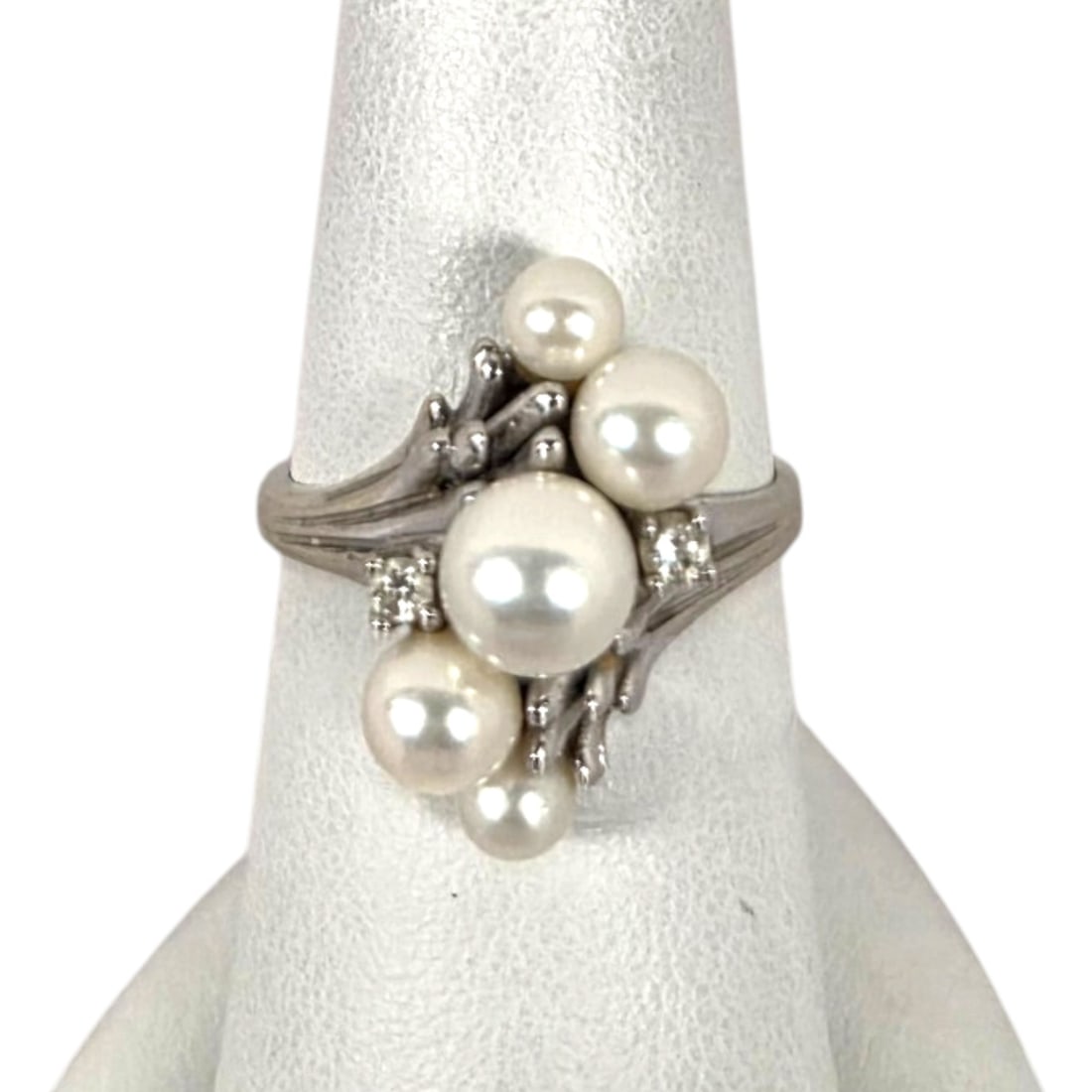 14 KT WHITE GOLD PEARL AND DIAMOND RING: 14kt white gold ring set with 5 pearls and 2 diamonds featuring a larger center pearl with graduated pearls on each side, together with a small prong set round cut diamond on each side, Size 7.5. Stam