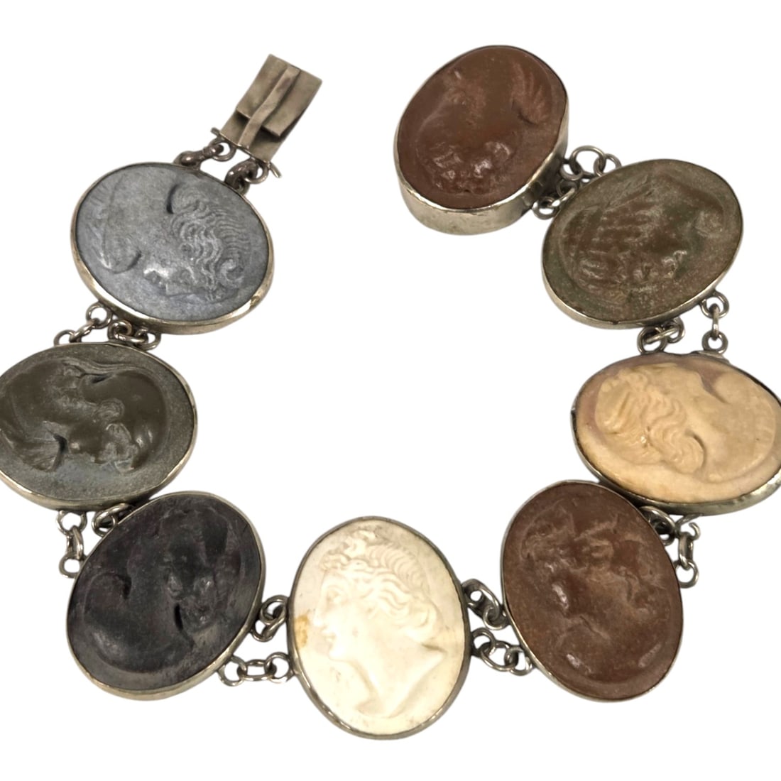 ANTIQUE 7 PANEL LAVA STONE CAMEO BRACELET: A lava stone cameo bracelet set in silver from the Grand Tour Era of the 19th century. Each of the 8 panels depict a deeply carved sculptural profile of a woman. Bracelet measures 6.5 and is in good,