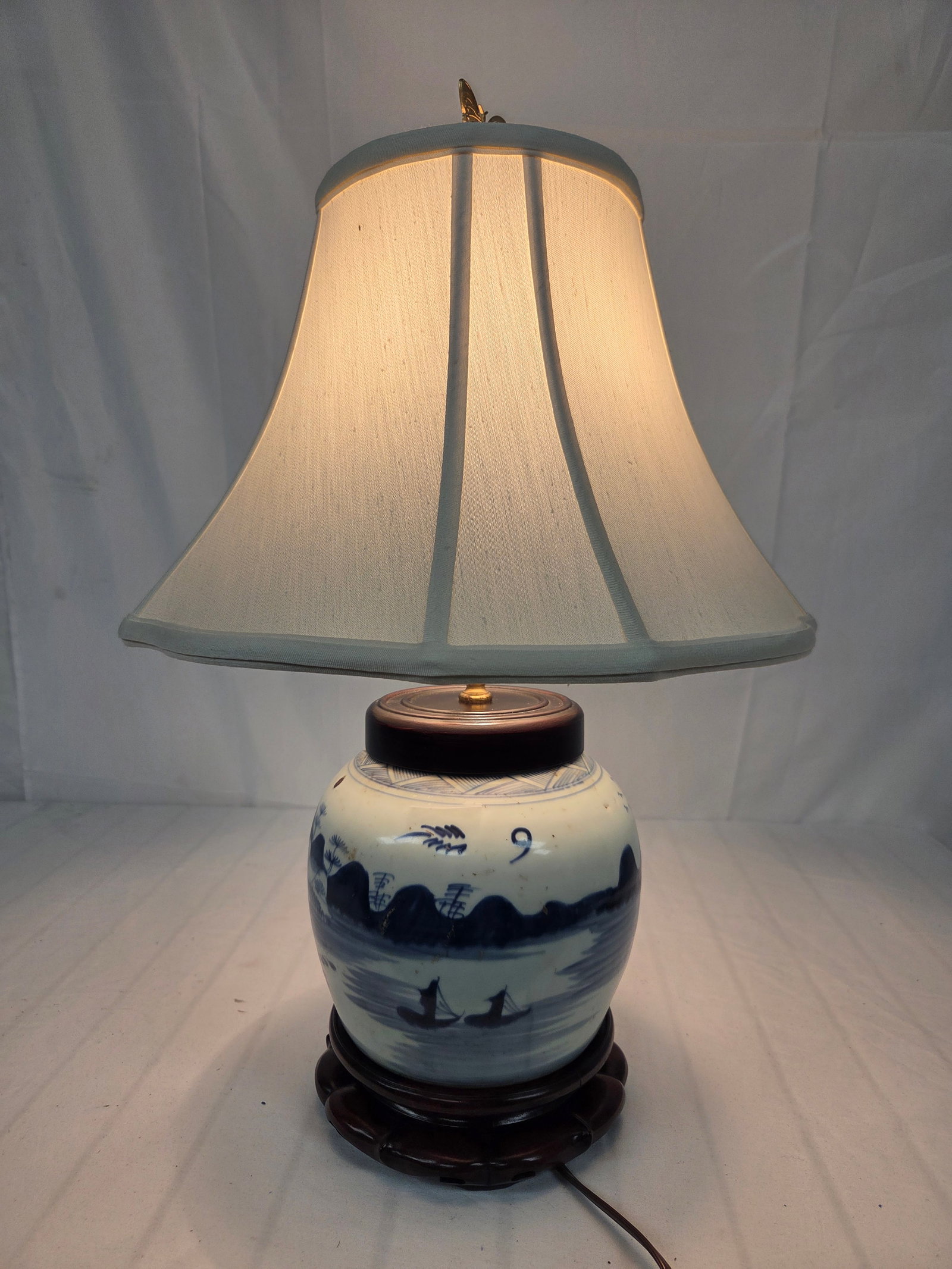 BLUE AND WHITE CANTON STYLE PORCELAIN TABLE LAMP: Vintage blue and white Canton-style porcelain ginger jar table lamp. Features a traditional coastal landscape depicting rolling mountains, pagodas, rivers, and small boats. Elevated on a classic