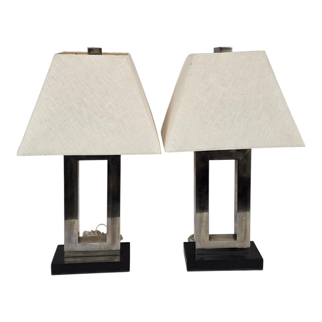 PR OF MODERN METAL OPEN FRAME TABLE LAMP: Pair of modern metal open frame silver tone lamps. Featuring a minimalist geometric open center body crafted from brushed metal anchored to a solid black rectangular base with a linen ivory colored