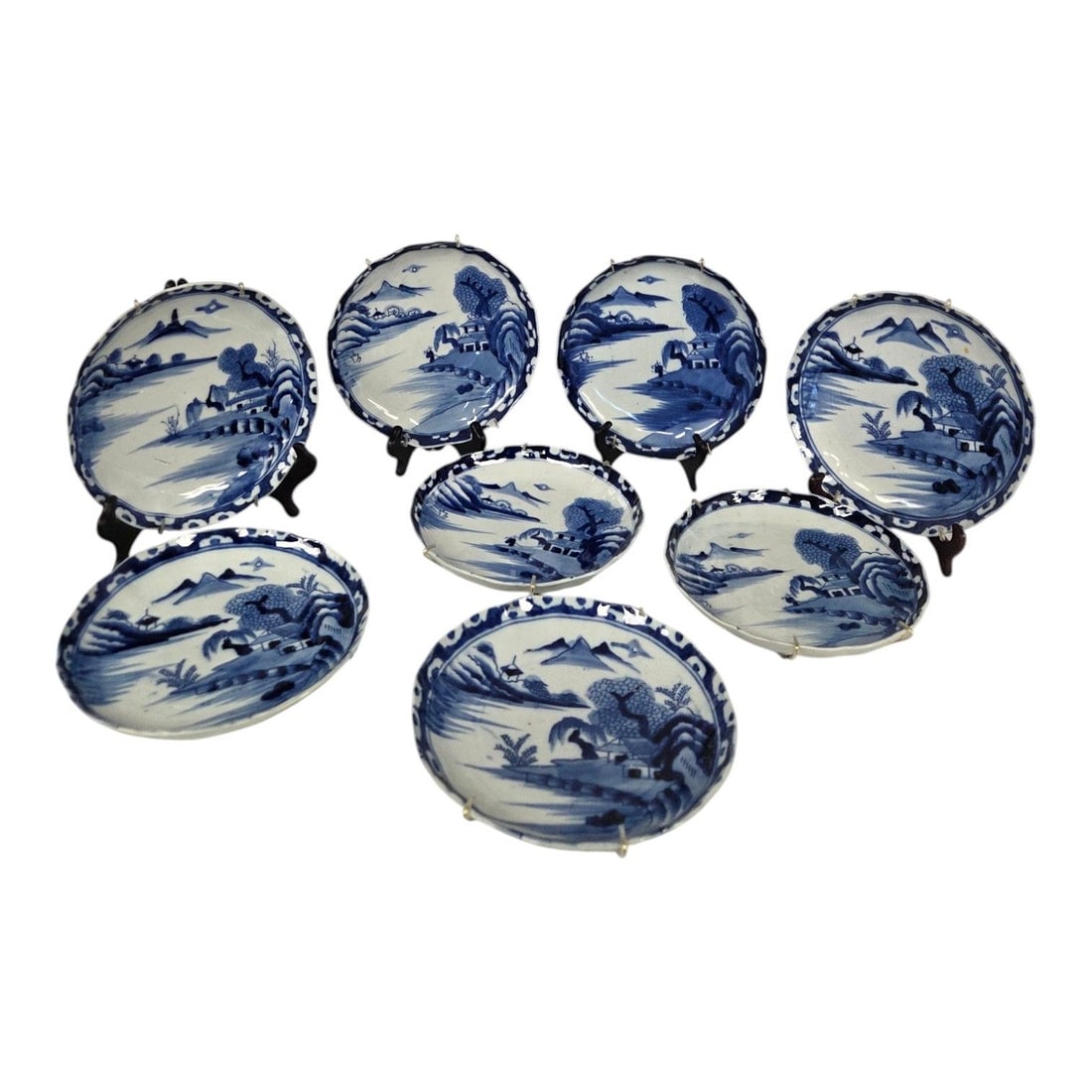 8 PC JAPANESE BLUE & WHITE PORCELAIN PLATE SET: 8 piece Japanese blue and white underglaze porcelain plates featuring a traditional hand painted scene depicting towering stylized mountin peaks, water, rolling hills, trees, and small pavilions.