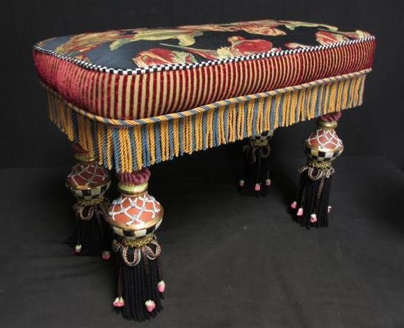 MACKENZIE CHILDS WHIMSICAL BENCH: A colorful eclectic bench by MacKenzie Childs. Floral tapestry fabric seat with velour sides, checked piping, and braided fringe, above highly decorated and painted baluster shaped legs. Measures 25" 