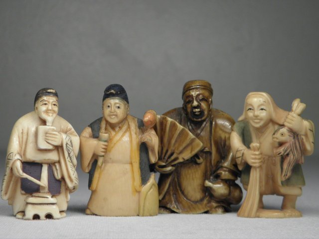 FOUR JAPANESE CARVED IVORY NETSUKE: STANDING MEN: Lot of four Japanese carved ivory netsuke, each depicting a different man standing. All have loop holes on the man's back, three netsuke are signed on base and colored, the stained netsuke is unsigned