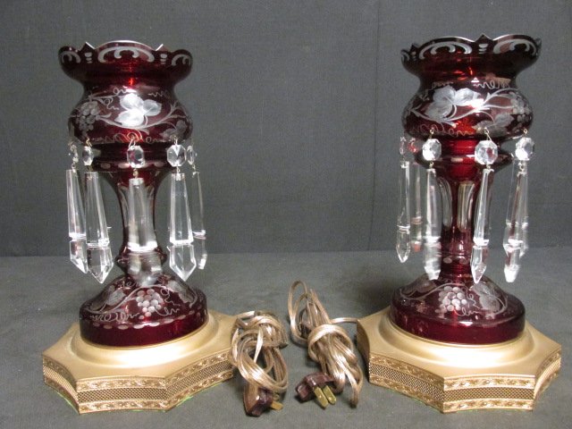 PAIR CRANBERRY CUT TO CLEAR CRYSTAL MANTEL LUSTRES: Pair of late 20th century cranberry cut to clear crystal mantel lustres. Each with an engraved grape vine motif, a reticulated brass tone base, 8 crystal prisms, and a single bulb light fixture in cen