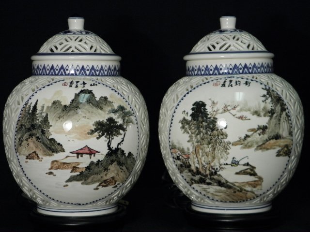 PAIR VINTAGE CHINESE PIERCED CERAMIC GINGER JAR LAMPS: Pair of vintage Chinese pierced ceramic lidded ginger jar lamps. Each ginger jar has a single interior light fixture and is mounted to a three footed carved wood base. The outsides are painted with va
