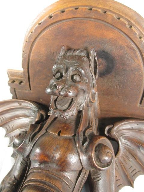 19TH C CARVED WOOD GARGOYLE WALL BRACKET: A continental 19th century carved Walnut wall bracket in the form of a winged gargoyle. Greek key pattern carved at edges of shelf, and with at eye hook attached at the top for hanging. Condition: rig