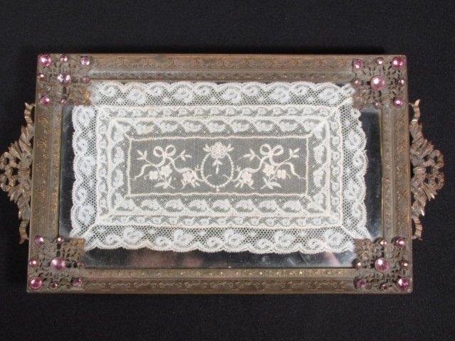 19TH C GILT BRONZE, GLASS & LACE VANITY TRAY: A 19th century jeweled and gilt bronze and glass vanity tray with a lace insert. Tray sits on four ball feet, and has pink jewels decorating each corner. Ribbon form handles on each end. Condition: ta