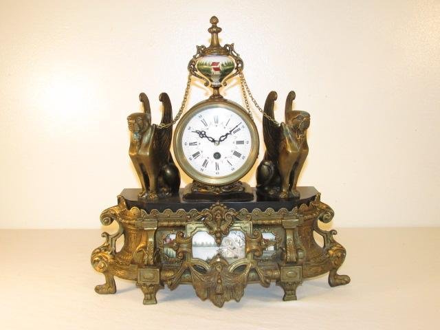 EGYPTIAN REVIVAL STYLE BRONZE MOUNTED MANTEL CLOCK: Egyptian Revival style bronze and porcelain mounted mantel clock. White enameled roman numeral face. Condition: clock runs but may need additional service for prolonged use, minor tarnishing and wear 