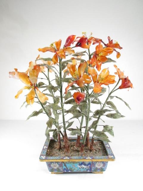 CLOISONNE, CARVED JADE & CARNELIAN FLORAL CENTERPIECE: A Chinese cloisonne, carved jade and carved carnelian floral centerpiece. Carved carnelian flowers with carved jade leaves, all in a scenic cloisonne planter. Unmarked as to maker. Condition: a few fl
