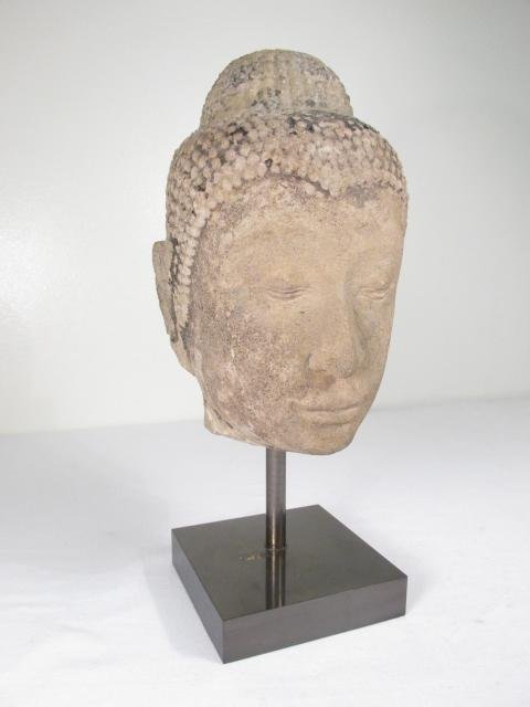 THAI CARVED STONE BUDDHA HEAD: Thai carved stone Buddha head mounted on a square metal base. Remains of a finish and gilding can be found in areas. Condition: heavy signs of age and wear, small losses to each ear lobe, blemish to m
