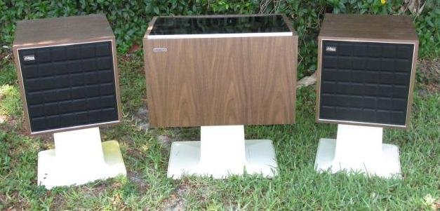 VINTAGE ZENITH MID CENTURY MODERN STEREO & SPEAKERS: Vintage Zenith mid century modern record player stereo and speakers. Each piece sits on an offwhite acrylic pedestal and has a faux wood finish. Condition: electronics untested, generally good cosmeti