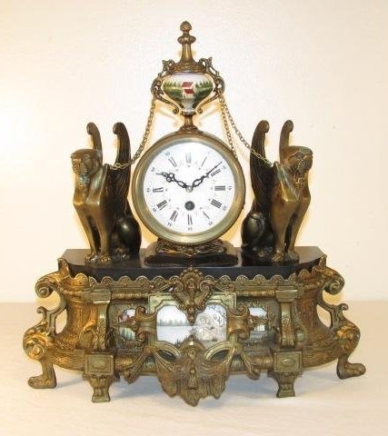 EGYPTIAN REVIVAL STYLE BRONZE MOUNTED MANTEL CLOCK: Egyptian Revival style bronze and porcelain mounted mantel clock. White enameled roman numeral face. Condition: clock runs but may need additional service for prolonged use, minor tarnishing and wear 