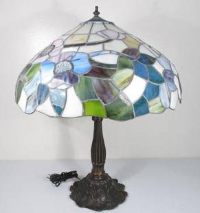 TIFFANY STYLE FLORAL STAINED & LEADED GLASS TABLE LAMP: Tiffany style stained and leaded glass table lamp in a floral pattern and with a patinated lily-pad decorated base. Condition: no chips or cracks to glass, minor corrosion to metal elements of shade,