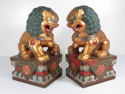 PAIR CHINESE POLYCHROME FINISH CARVED WOOD FOO DOGS: Pair Chinese polychrome finish carved wood foo dogs. Circa late 19th, early 20th century. One with foot resting on a ball, and the other with a foot resting on a smaller dog. Both are elaborately