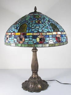 TIFFANY STYLE STAINED & LEADED GLASS TABLE LAMP: LILY: Tiffany style stained and leaded glass table lamp with a patinated metal lily-pad form decorated base. Combination of slag and stained/textured glass used for shade. Condition: generally good, minor