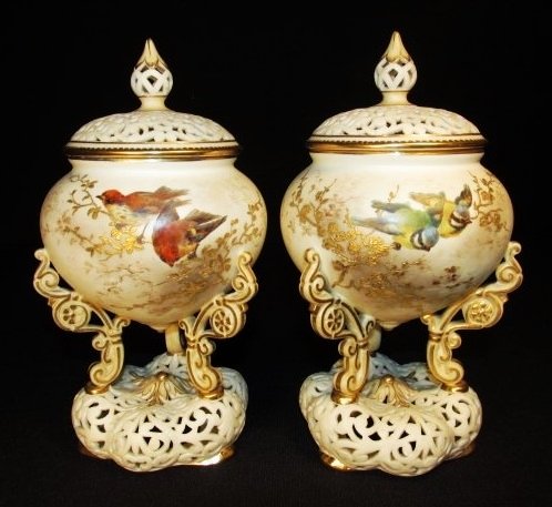 PAIR ROYAL WORCESTER PORCELAIN COVERED POTPOURRI JARS: Pair of Royal Worcester porcelain covered potpourri jars. Each has a reticulated lid and base, and is supported by three scrolled and gilt legs. Each jar is marked on base "Royal China Works Worcester