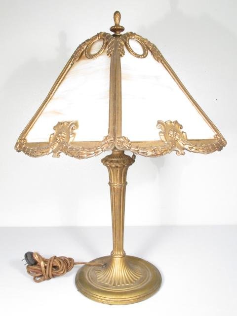 EDWARD MILLER SLAG GLASS PATINATED METAL TABLE LAMP: Early 20th century Edward Miller slag glass and patinated metal table lamp. Six panel white & cream colored slag glass shade. Marked on side of socket. Condition: seams between panels are slightly spl