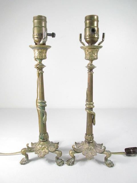 PAIR FRENCH BRONZE CLAW FOOT CANDLESTICKS: Pair of French bronze claw foot candlesticks mounted as table lamps. The mid section of each lamp is wrapped by a small bronze snake. Unmarked. Condition: signs of age and wear to bronze and lamp hard