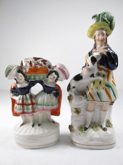TWO STAFFORDSHIRE PORCELAIN FIGURINES: Lot of two 19th century Staffordshire porcelain figurines. One figure depicts a woman with a dog, and the other figure depicts two women carrying a dog on a pillow. Unmarked. Condition: consistent cra