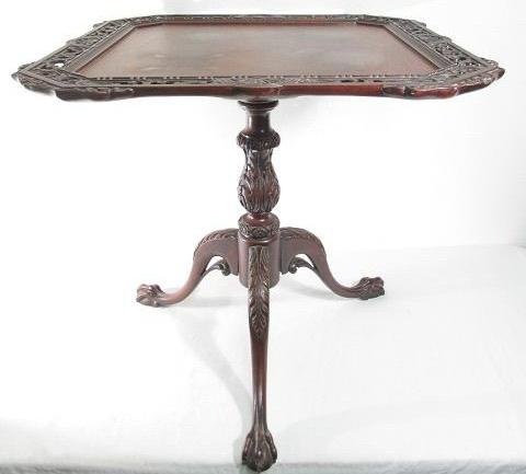 CARVED MAHOGANY TEA TABLE WITH FRETWORK EDGE: Early 20th century mahogany tea table with a carved fretwork edge. Tripod base, baluster carved pedestal, with ball and claw feet and a flame mahogany finished surface. Condition: good, minor signs of