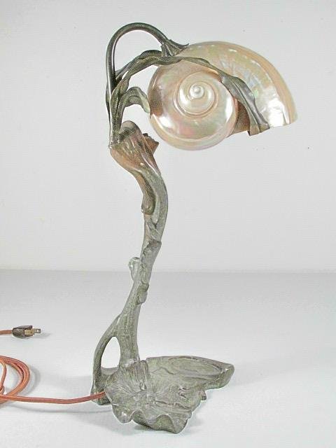 ART NOUVEAU PATINATED METAL FIGURAL SHELL LAMP: Art Nouveau patinated metal figural shell lamp. Features a woman's head gazing up towards the shell lamp shade. Beautiful iridescent color shines through the shell. Unsigned. Condition: early repair t