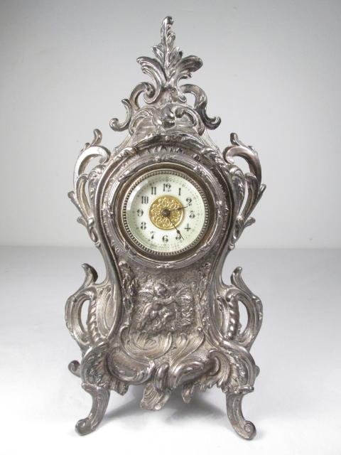 NEW HAVEN ROCOCO STYLE SILVER PLATED MANTEL CLOCK: New Haven Rococo style silver plated mantel clock measuring 11.25" tall x 6.5" wide x 3.25" deep. Late 19th/Early 20th century. Arabic numeral dial, marked by maker at base of face. Condition: origina