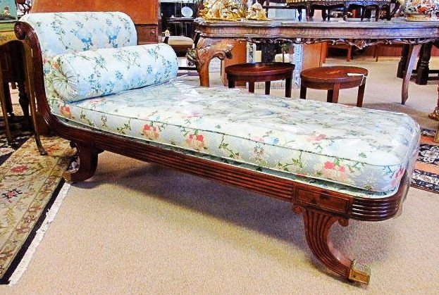 19TH C EMPIRE STYLE MAHOGANY CHAISE LOUNGE: 19th century Empire style mahogany chaise lounge with an upright rolled end, raised on curved reeded legs ending in brass capped feet with casters and fitted with a long cushion and a bolster. Measure