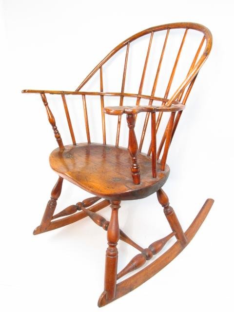 EARLY 19TH C CARVED WOOD BOW BACK WINDSOR ROCKING CHAIR: An early 19th century carved wood bow back Windsor rocking chair measuring 34.5" tall x 22" wide and approx. 28" deep. Condition: signs of age to finish, loose metal braced repair (metal brace under a