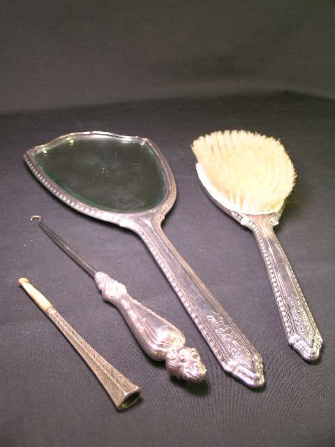 STERLING SILVER VANITY SET 4 PCS: Lot: 253: STERLING SILVER VANITY SET 4 PCS - Mirror measures 13" long x 5" wide, brush is 10" long x 3" wide and both pieces are monogrammed "P". Boot hook is 8" long and cigarette holder is 4 3/4" lo