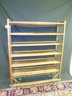 1920'S - 30'S PRIMITIVE WOOD COBBLERS SHOE RACK: Lot 511: 1920'S - 30'S PRIMITIVE WOOD COBBLERS SHOE RACK - Mounted on flat castors. Brace missing on 3rd row from top (see photo). Shelves bowing from age. Scratches, dings, splits. Measures 55" high