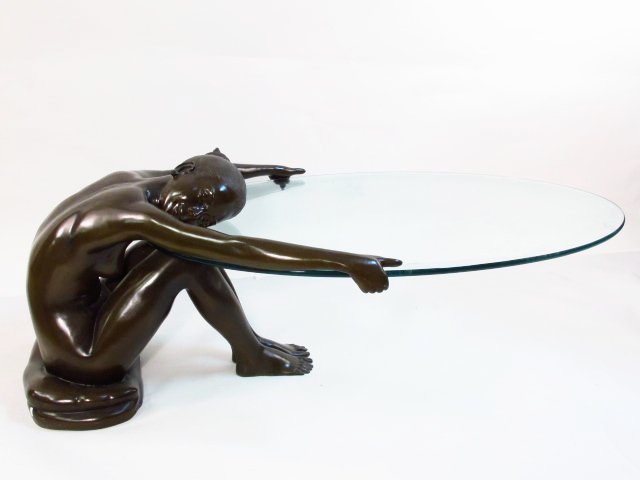 BRONZE & GLASS FIGURAL NUDE COFFEE TABLE: Bronze and glass sculptural figural nude coffee table. Depicts a woman holding up the glass surface. Unsigned. Condition: a few small signs of use to table base, no chips or cracks, to glass, see imag