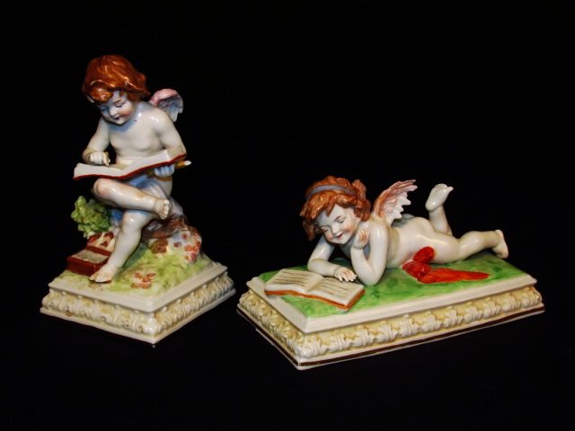 TWO RUDOLSTADT GERMAN PORCELAIN CHERUB FIGURINES: Two 19th c Rudolstadt German porcelain cherub figurines. One depicting a sitting cherub, and the other reclining, both reading books. Marked on base with "Germany" and Rudolstadt crown mark. Condition