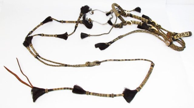 ANTIQUE PRISON MADE HORSE HAIR BRIDLE, REINS QUIRT: Multi-color horse hair bridle, New Mexico, circa 1900, hand woven with diamond designs, 19 tassels, four bakelite rings, two glass domed horse bridle rosette buttons, woven "good luck" browband, bit a